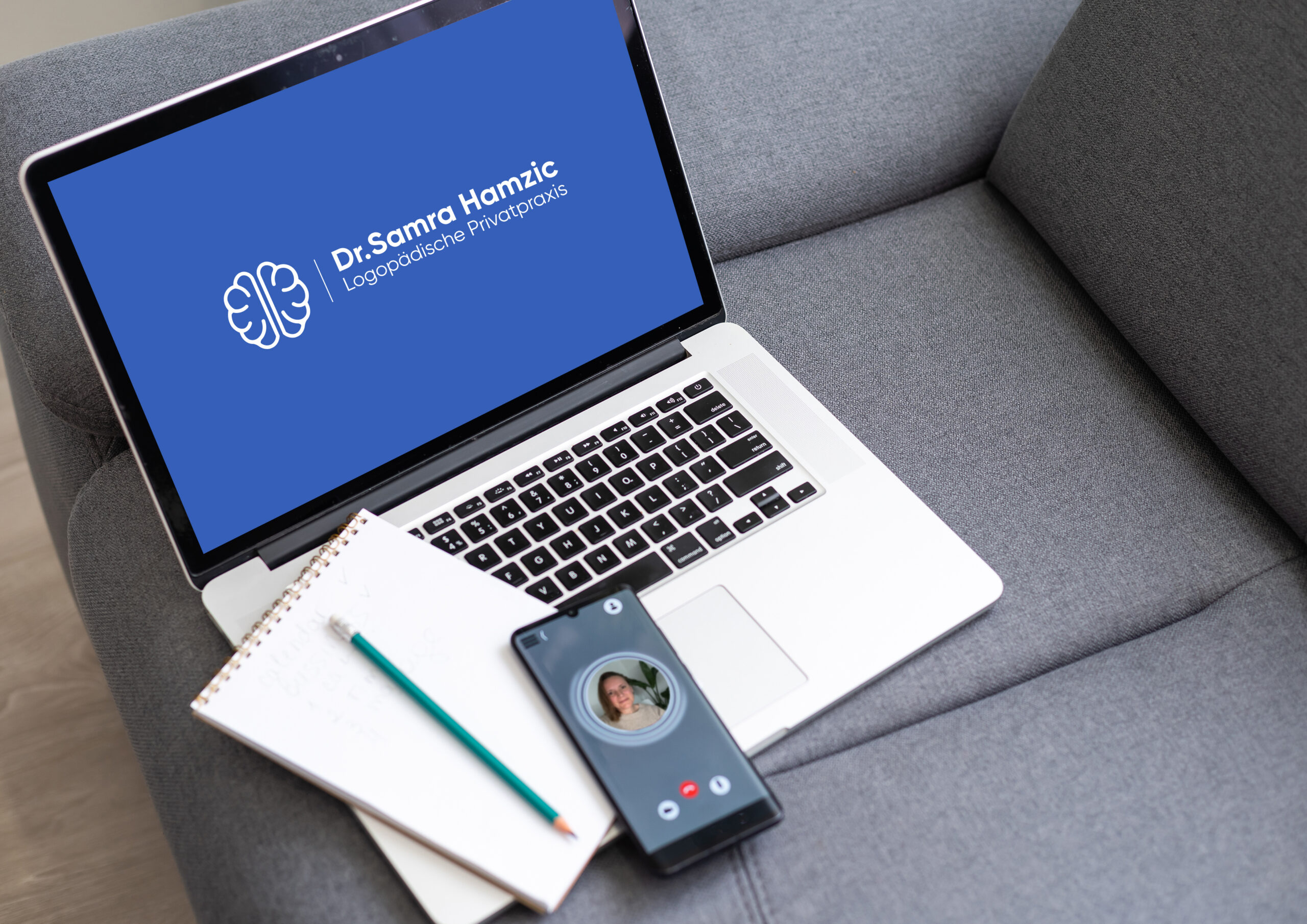 Technische Utensilien wie Laptop, Handy und Notizbuch sind bereit für die Online-Therapie.